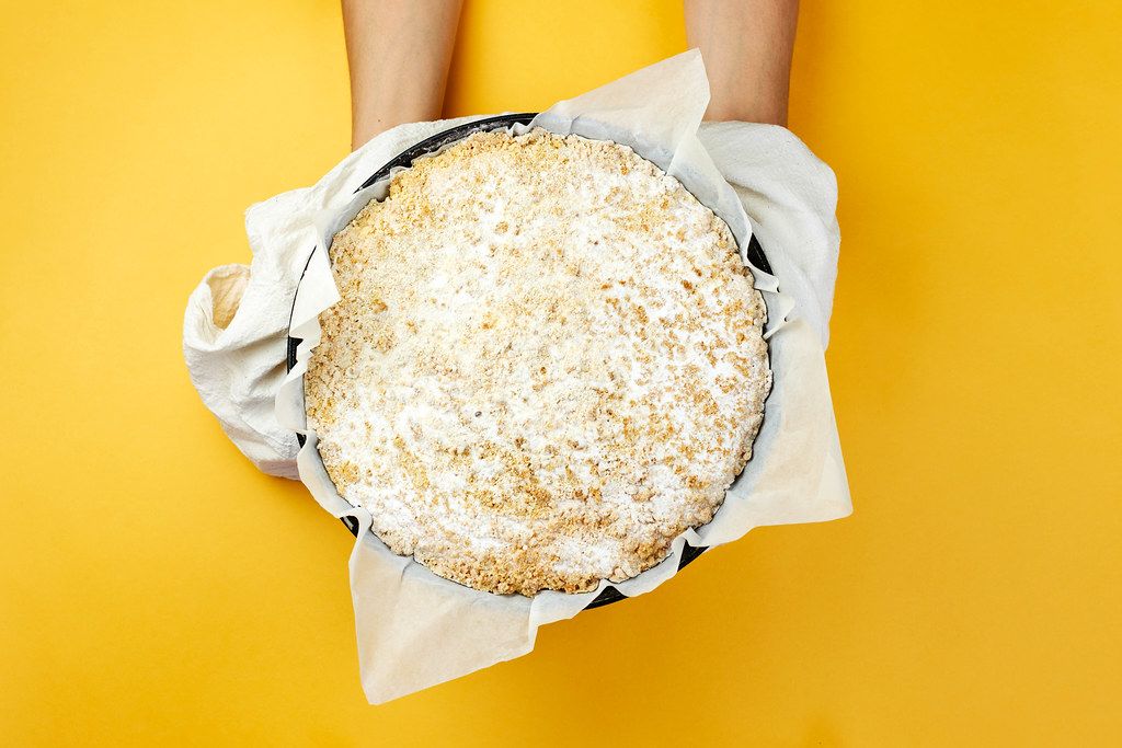 Woman holding freshly baked cottage cheese pie over the yellow background