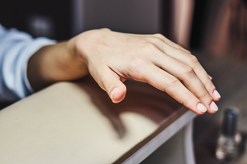 Woman holding her hand on manicure table