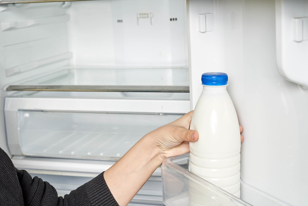 Woman takes out fresh yogurt from fridge