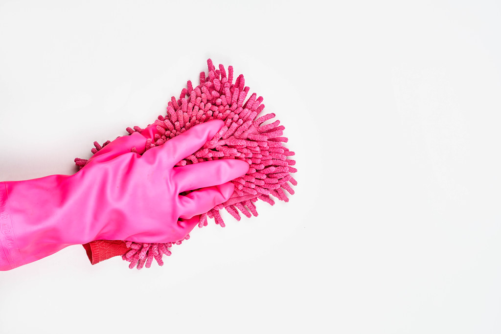 Woman wearing pink rubber protective glove and cleaning white surface, spring cleaning