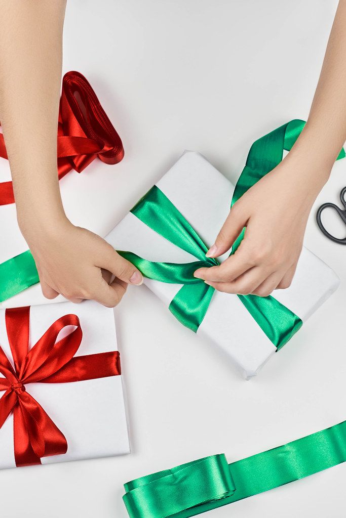 Woman wrapping beautiful Christmas gift in the white paper