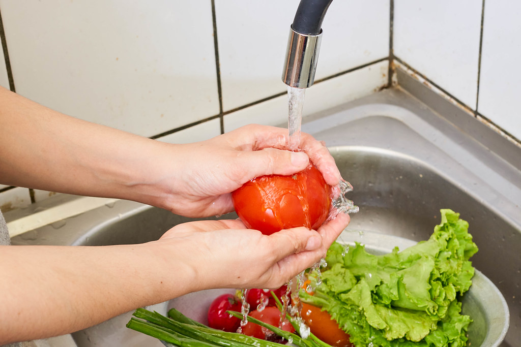 Woman's hands wash ripe tomatoes