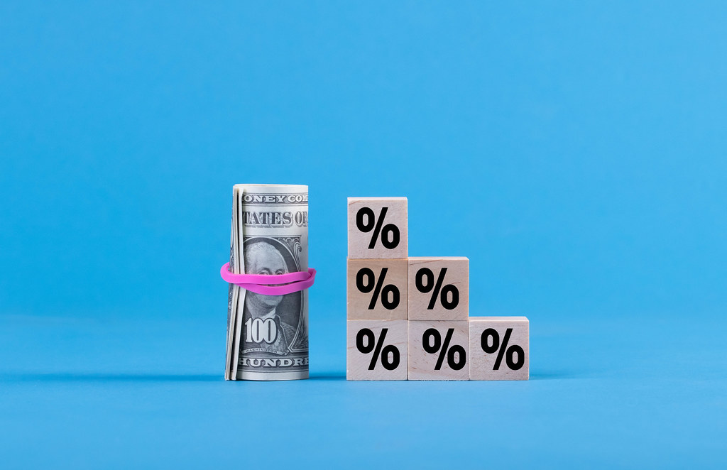 Wooden blocks with percentage sign and money roll on blue background
