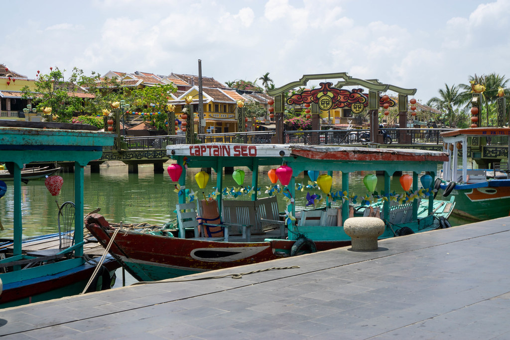 Wooden Tourist Boats with Colorful Lanterns with Bridge of Light in the Background in the Ancient Town of Hoi An, Vietnam