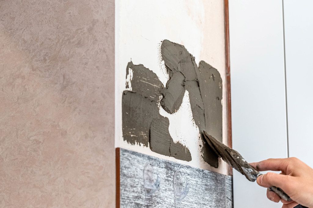 Workman apply a trowel on the wall mixture for gluing tiles