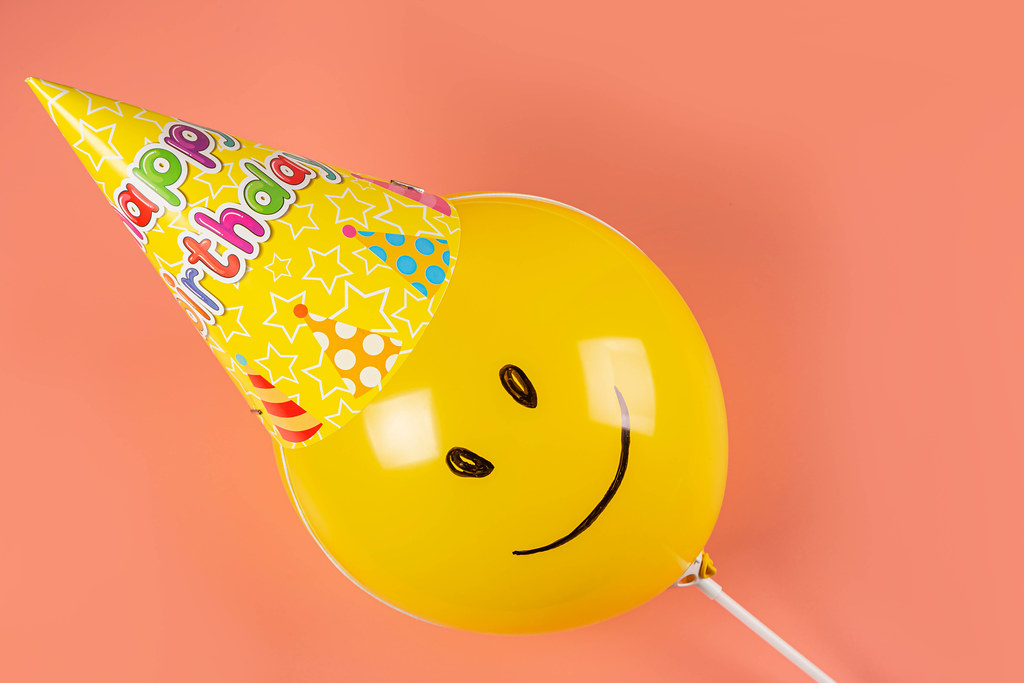 Yellow balloon in a cone hat on a pink background