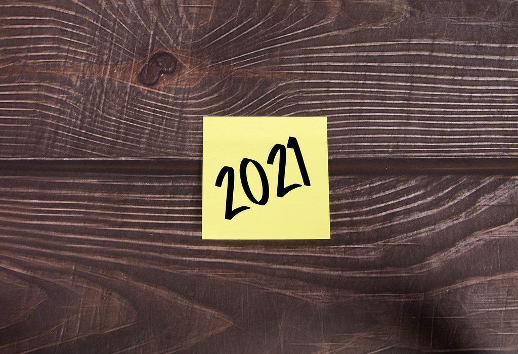 Yellow sticky note with 2021 text on wooden table