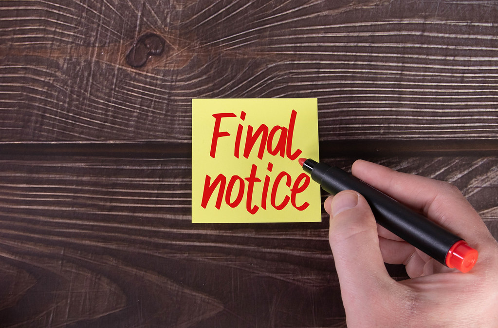 Yellow sticky note with Final notice text on wooden table