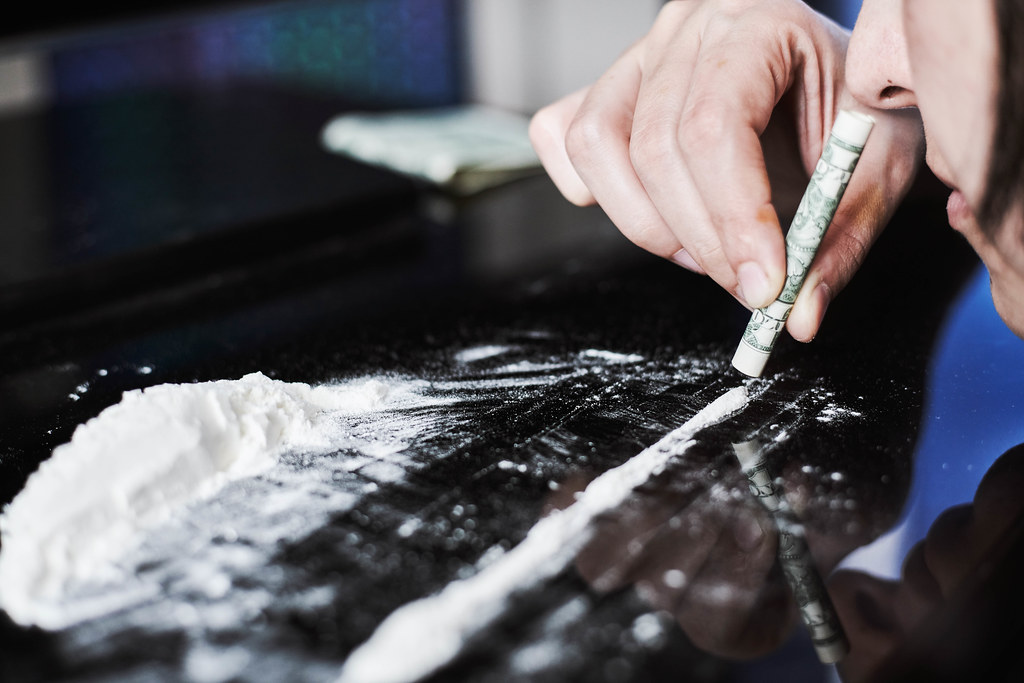 Young addicted woman sniffing a line of cocaine