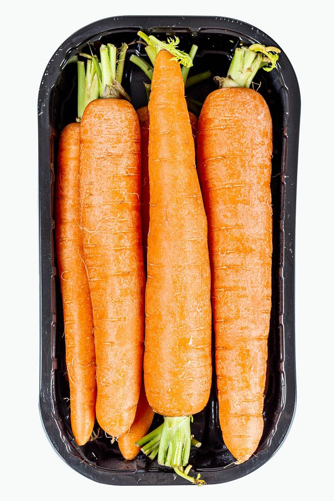 Young carrots in plastic packaging, top view