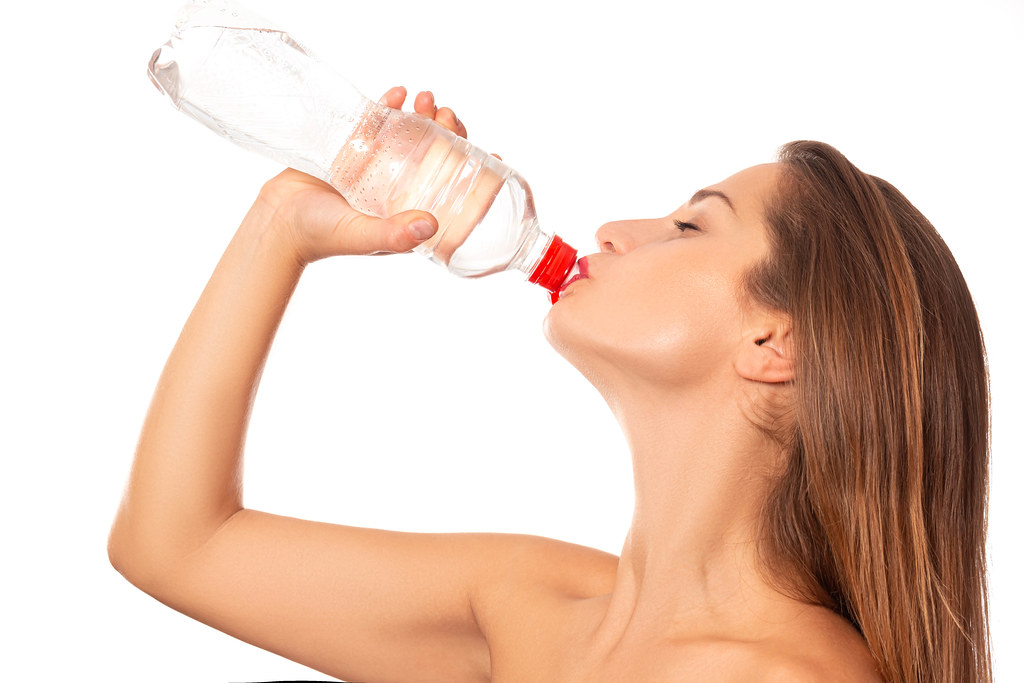 Young woman drinking water, on white background