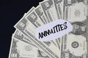 "Annuities" Text auf kariertem Zettel mit 100-Dollar-Scheinen
