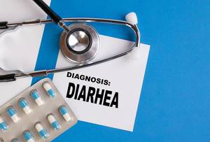 "Diagnose: Durchfall", geschrieben auf blauem Ärzteordner, neben Medikamenten und Stethoskop