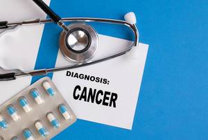 "Diagnose: Krebs", geschrieben auf blauem Ärzteordner, neben Medikamenten und Stethoskop