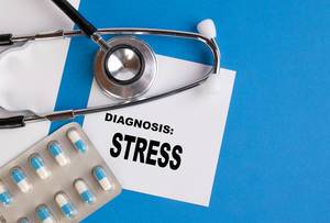 "Diagnose Streß", geschrieben auf blauem Ärzteordner, neben Medikamenten und Stethoskop