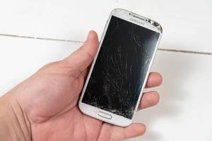 "Zeit für ein Upgrade" - Konzeptbild: Hand hält ein Handy mit zerschlagenem, kaputten Display vor weißem Hintergrund