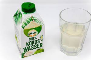 100% coconut water in a beverage carton next to a filled glas