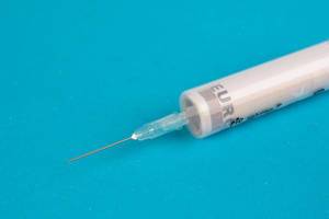 50-Euro-Schein in einer Injektionsspritze für medizinische Untersuchungen, auf blauem Hintergrund