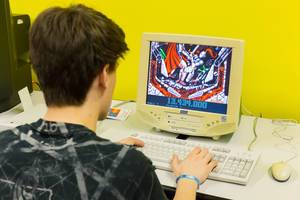 A boy is playing a computer game on an old school computer desktop