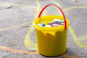 A bucket of colored chalk for drawing on the asphalt