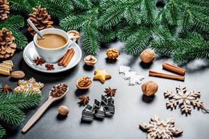 A cup of coffee in Holiday Decoration - Nuts, Cinnamon, Christmas-tree branches, Baking forms