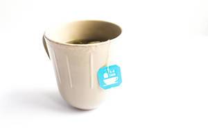 A cup of tea with a tea bag on white background