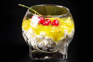 A glass of cottage cheese dessert with fresh kiwano and red currants on a black background (Flip 2020)