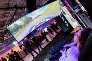 A man is playing a car game at the Samsung stand with a wide curved screen
