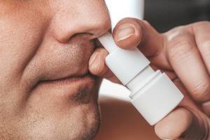 A man sprays medicine in his nose. Runny nose treatment concept (Flip 2019)