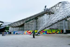 A man taking a selfie in front of Munich Olympiastadion (Olympic Stadium)