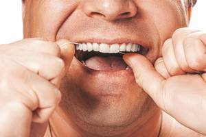 A man uses dental floss to clean his teeth (Flip 2019)