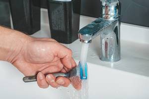 A man washes a razor under the faucet in the bathroom (Flip 2019)