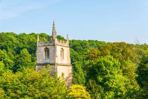 A medieval church tower surrounded by green tree crowns