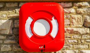A plastic box with a lifebuoy fixed to the wall above the water