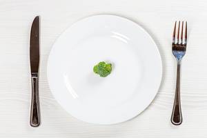 A small piece of green broccoli on a white plate as a symbol of weight loss (Flip 2019)