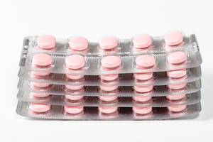 A stack of pink tablets in blisters. Drug treatment concept (Flip 2019)
