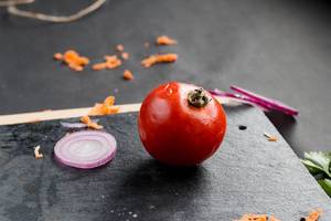 A tomato and other vegetables in the kitchen , dark background