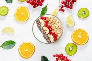 A top view of a bowl of oatmeal on a white wooden background with fresh fruits and berries (Flip 2019)