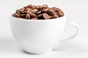 A white Cup full of fried coffee beans