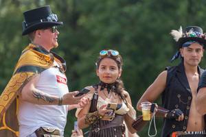 A woman and two men enjoy Tomorrowland in hats and futuristic sunglasses