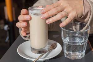 A woman drinks a Latte Macchiatto at a cafe in Rome