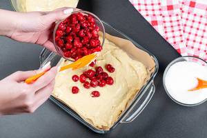 A woman puts pitted cherries in the pie dough