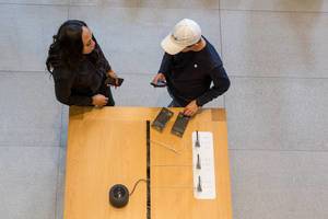 A woman with a smartphone in her hand gets assistance from an employee at the Apple