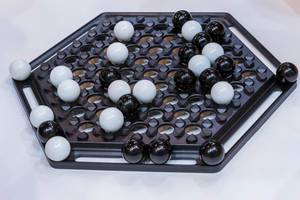 Abalone: classic board game with hexagonal board and black and white marbles on white background