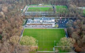 Aerial photo of football pitches surrounded by trees with a building and parking lot