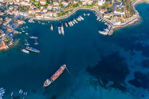 Aerial photo of the shore of Greek island Spetses in summer & boats and cargo ship in the harbour in the blue Aegean Sea