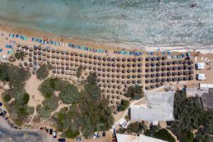 Aerial view and top view of Santa Maria beach full of tourists on summer vacation, under parasols made of bast