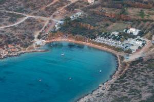 Aerial view of a bay with beach section and blue sea, in front of the Greek island Paros