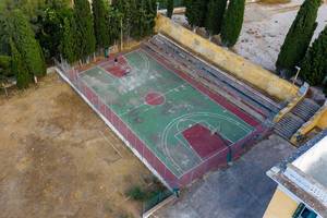 Aerial view shows two children on an old basketball court at Ligoneri Beach at Spetses, Greece