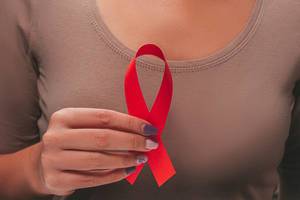 Aids Awareness. Female hands holding red AIDS awareness ribbon (Flip 2019)